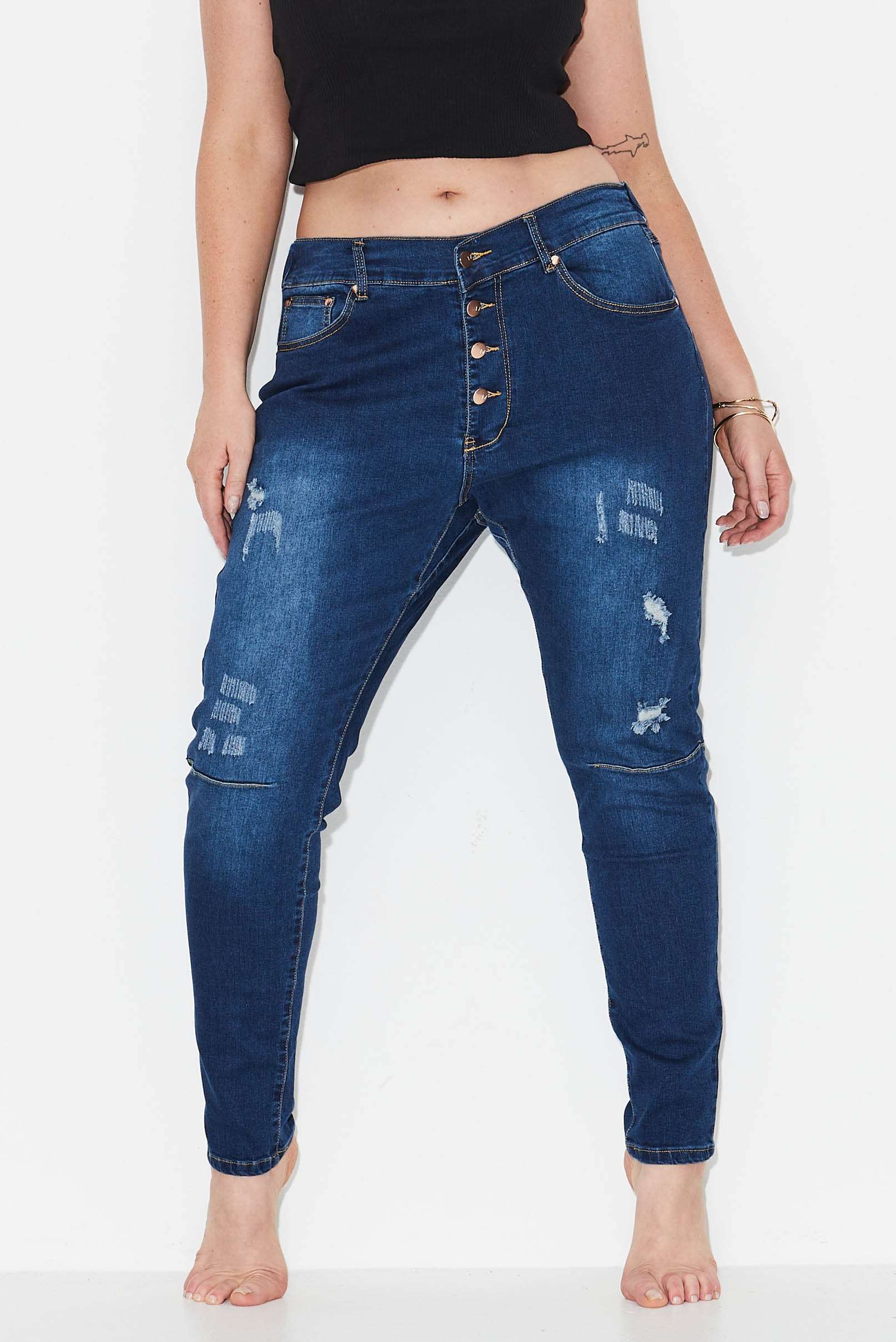 Model wears dark blue plus size tapered leg, ripped  jeans with exposed button front 