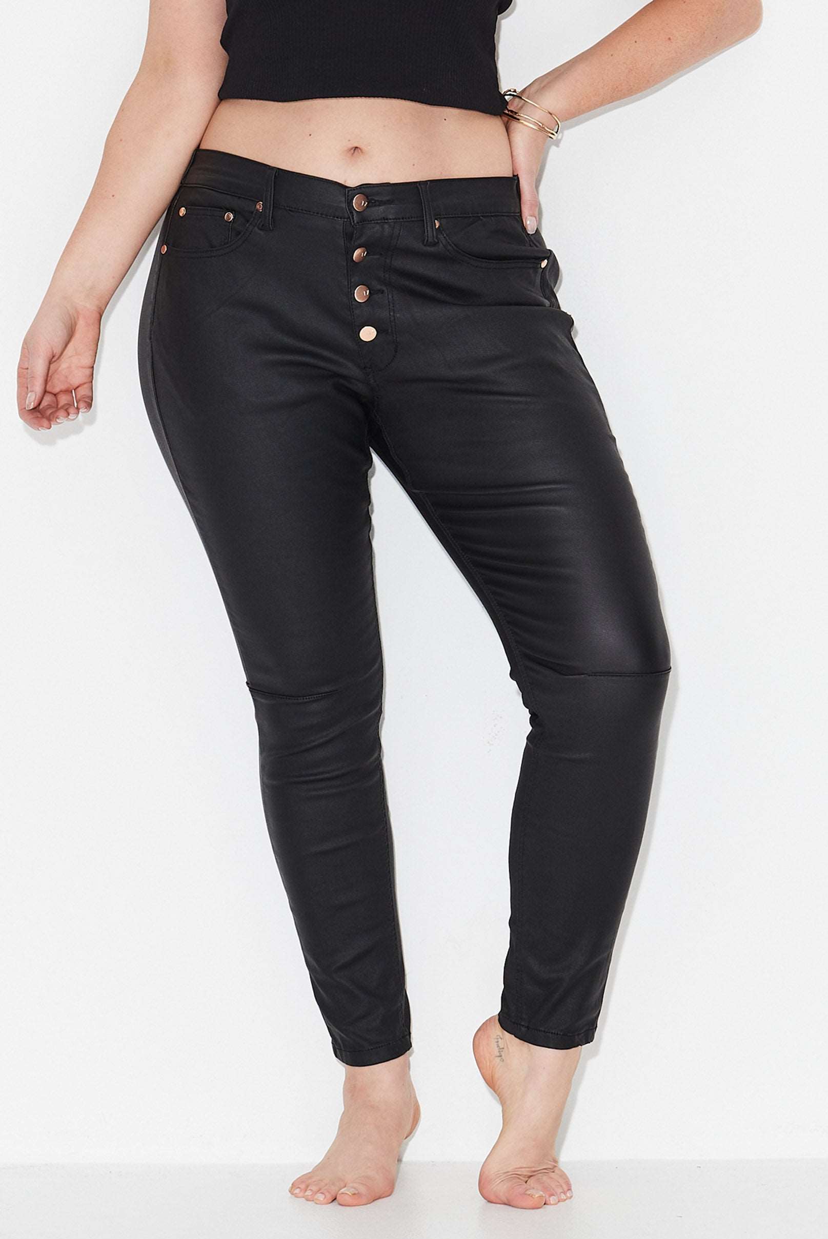 Model wears black plus size jeans with tapered leg and exposed button front 
