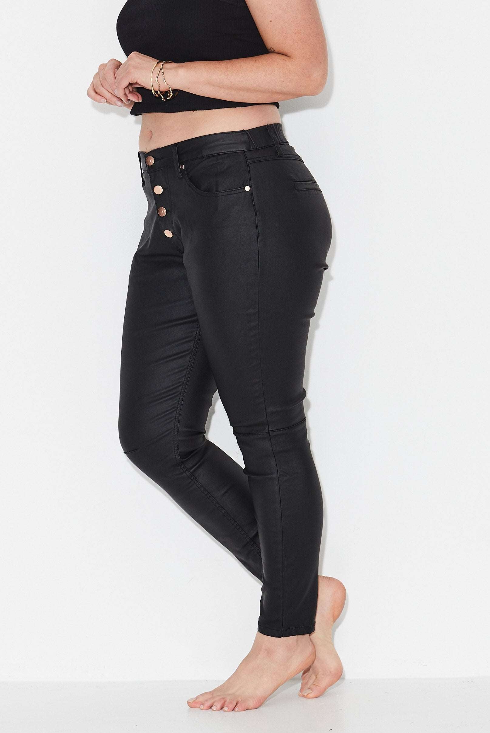 Model wears black plus size leather look jeans with exposed button front 