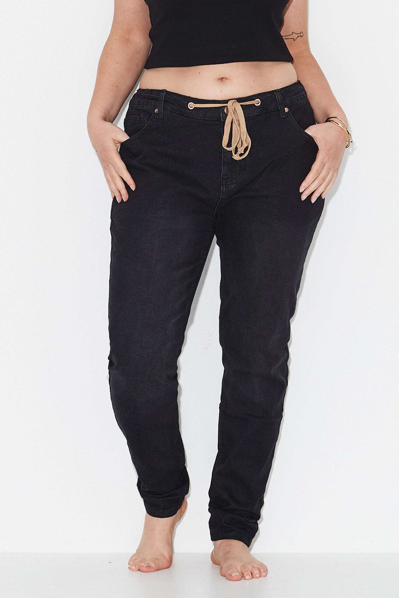 Model wears black slim leg plus size jeans with adjustable waist tie