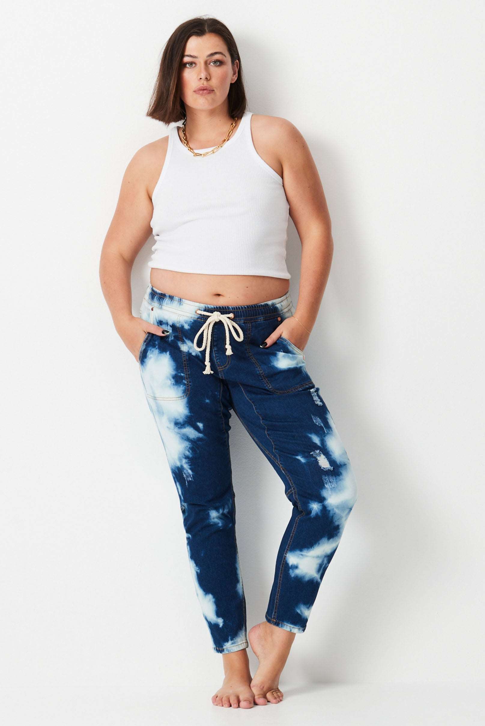 Model wears dark blue tie dyed stretch denim plus size jeans. with elastic waist and tapered leg.