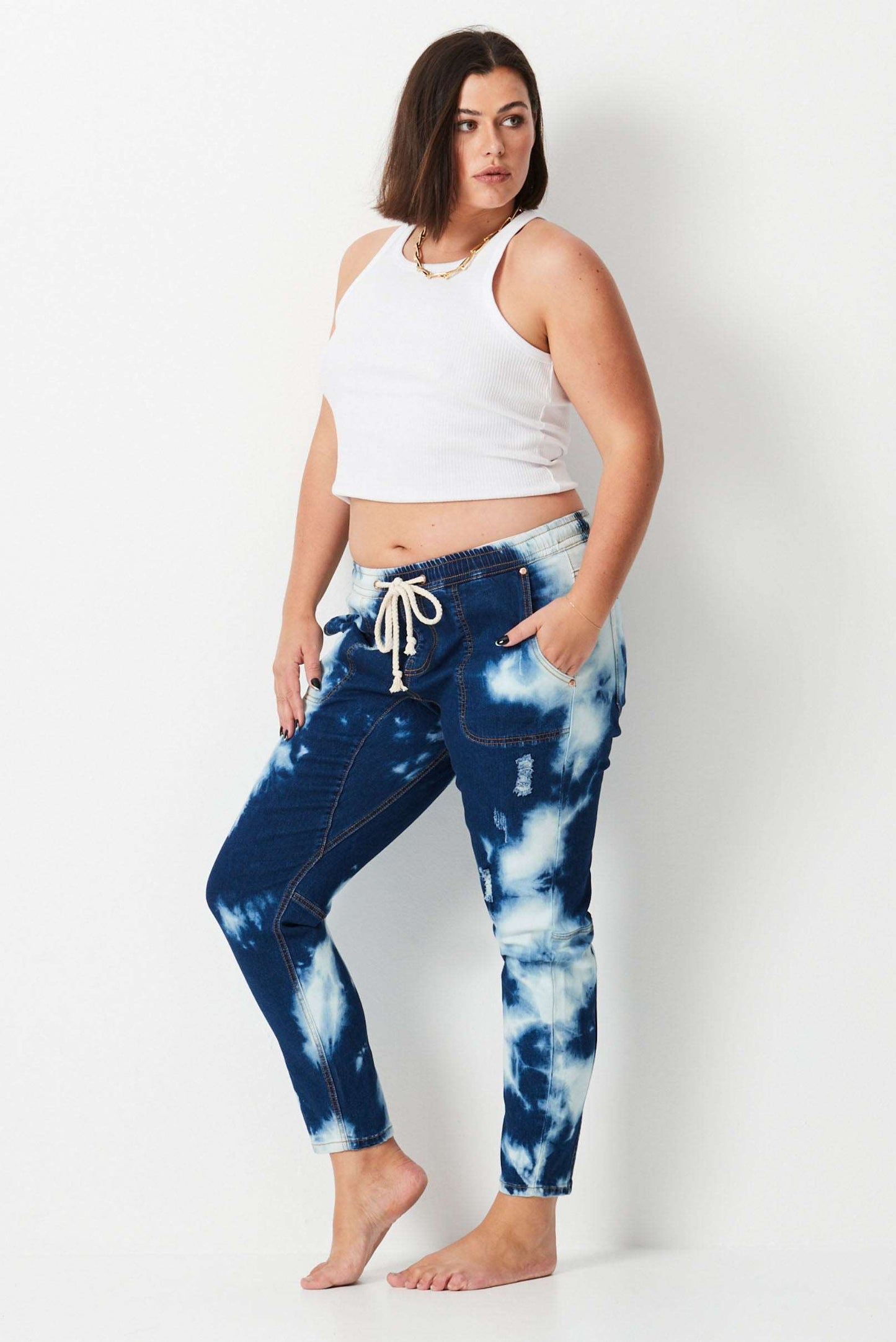 Model wears plus size dark blue tie dye denim jeans. with elastic waist and tapered leg.