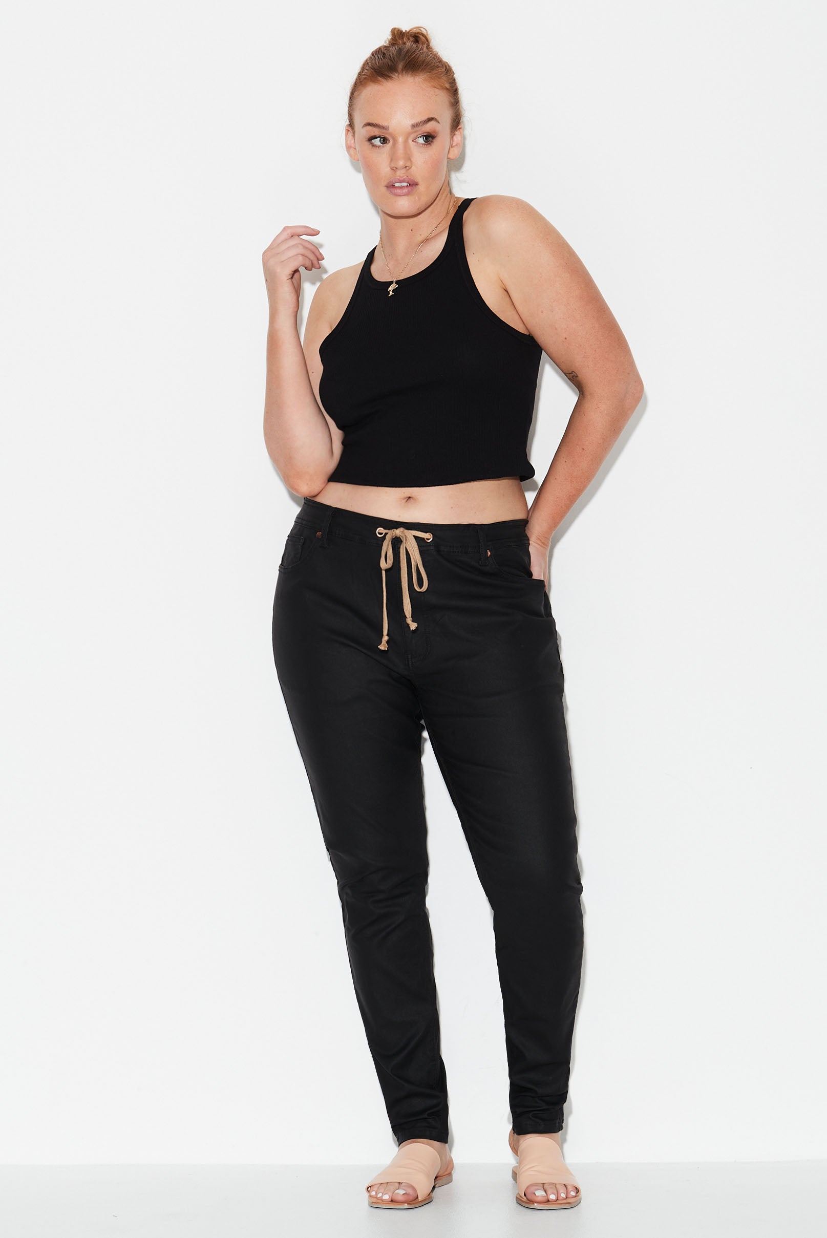 Model wears black leather look stretch denim plus size skinny jeans