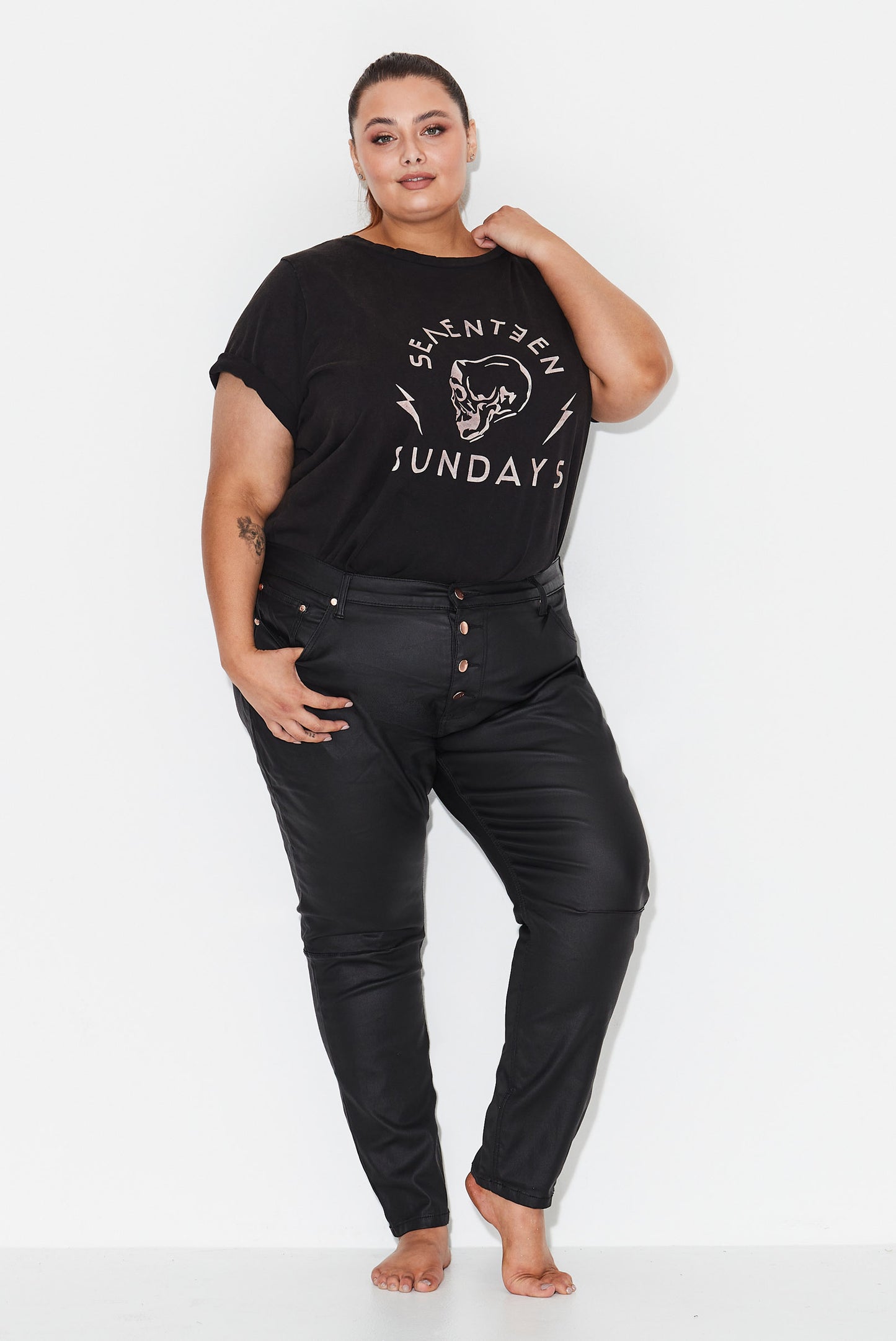 Model wears black  leather look plus size jeans with exposed button front 